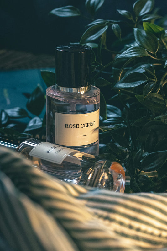 a bottle of perfume sitting on top of a bed next to a plant
